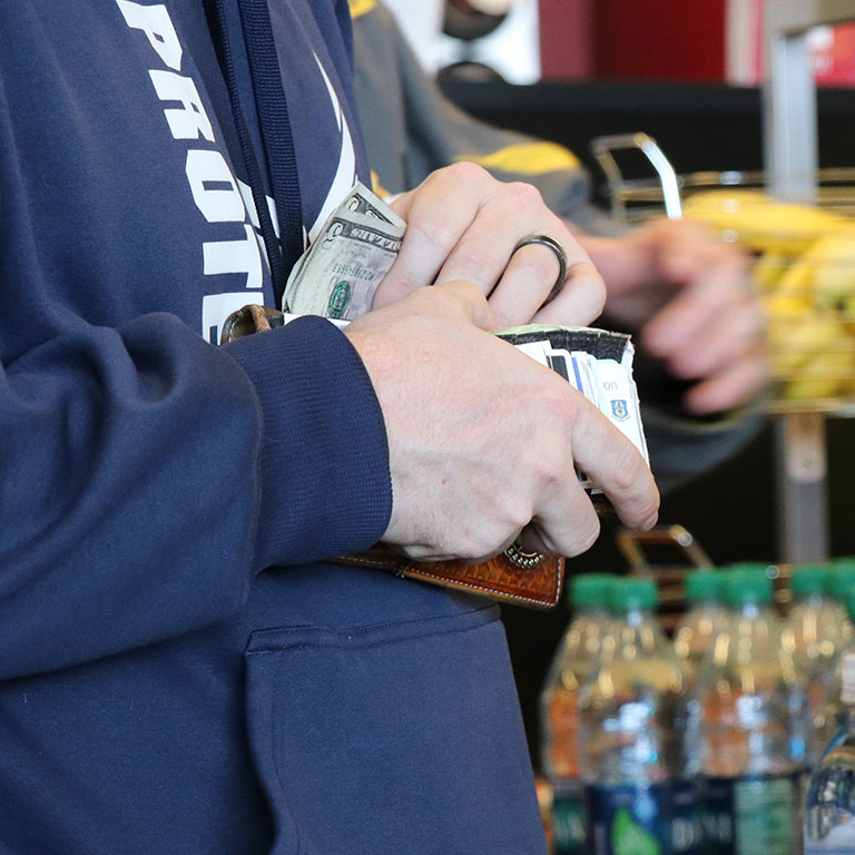Close up of a student putting money in their wallet.